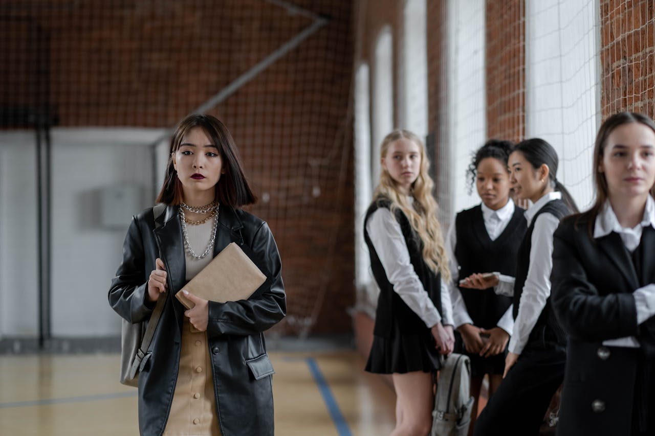 Group of diverse students in a school hall wearing uniforms and interacting.